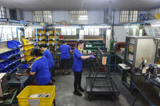 Employees work on pneumatic tools in a U-shaped production cell. Employees work on pneumatic tools in a U-shaped production cell.